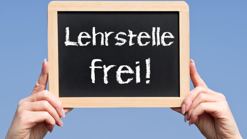 Hände halten eine Tafel mit der Aufschrift "Lehrstellen frei" hoch. 