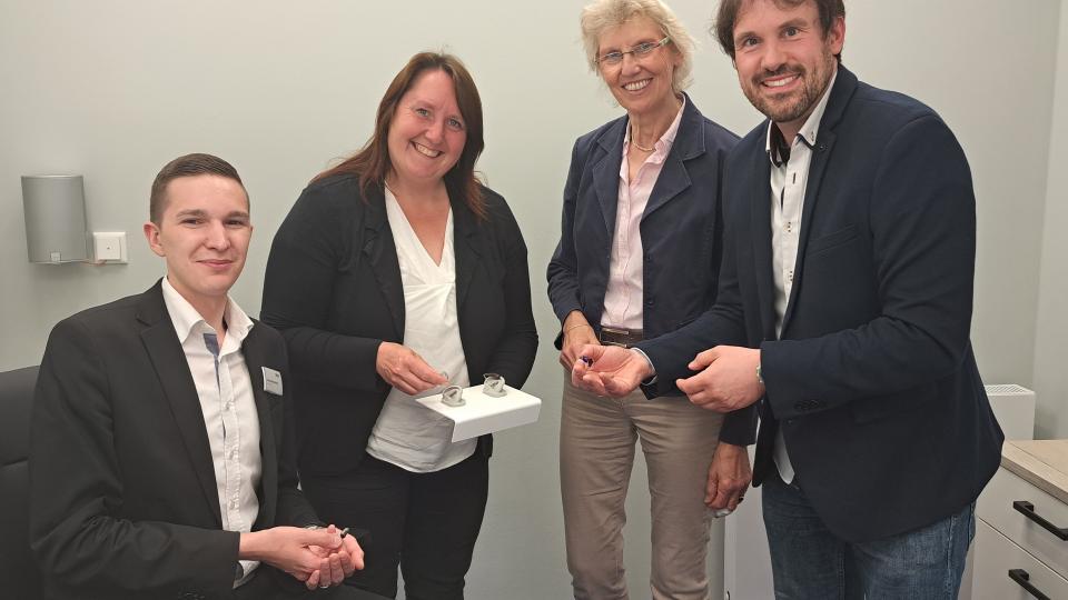 Er hat das perfekte Berufsfeld für sich gefunden: Hörgeräteakustiker Christofer Macholla (links) erläutert gemeinsam mit Meisterin Kaya Harbaum-Salewski (2.v. links) Hildegard Hesselbarth, ArbeitgeberService, und Michael Kelka, MaßArbeit-Bereichsleiter, die neuste Technik in Sachen Hörgeräte.  Foto: MaßArbeit / Kimberly Lübbersmann 