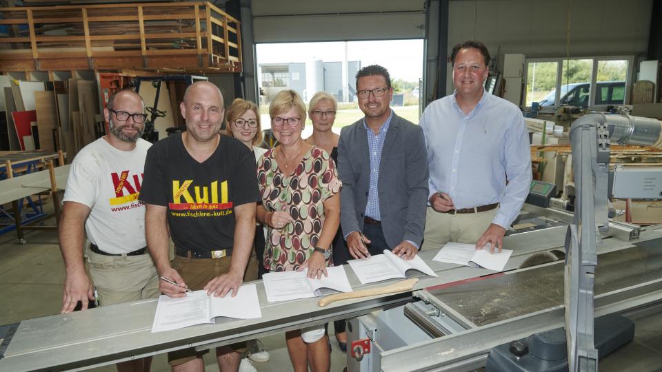 Sie besiegelten die neue Kooperation zwischen der Geschwister-Scholl-Oberschule in Bad Laer und der Tischlerei Kull (von links): die Geschäftsführer Tobias und Markus Kull, Annika Schütte von der Servicestelle Schule-Wirtschaft, Schulleiterin Stefanie Baalmann, die Berufsorientierungsbeauftrage und Fachberaterin beim Regionalen Landesamt für Schulen und Bildung, Mareike Himmelreich, MaßArbeit-Vorstand Lars Hellmers sowie Bürgermeister Tobias Avermann. 